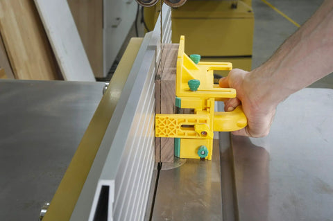 Hand using Kickback Buster 3D Push Block With Gravity Heel Kit For Table Saws on a wooden piece for precise cutting.