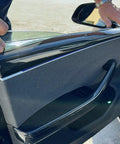 Person installing Autoclave Pressed Real Dry Carbon Fiber Door Panel Overlays Fits Tesla Model 3 Highland And Model Y in a vehicle.