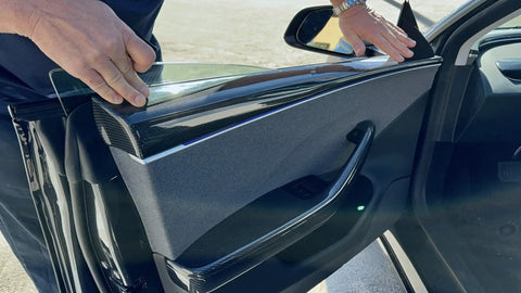 Person installing Autoclave Pressed Real Dry Carbon Fiber Door Panel Overlays Fits Tesla Model 3 Highland And Model Y in a vehicle.