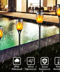 Solar Torch Lights With Flickering Flame 16 Pack 12 LED Outdoor Landscape Lighting Tiki Torches displayed by a pool