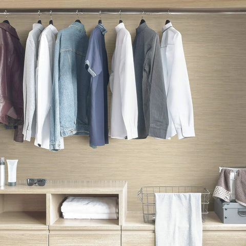 Cream Tibetan Faux Grasscloth Peel And Stick Wallpaper on closet wall, clothes hanging, textured neutral look, easy install.