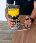 Close-up of a person using a 6X9 Router Base Plate In Clear Acrylic Sets A Dead On Fit For Dewalt Dwp611 And Dcw600b on wood.