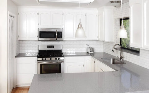 Modern kitchen with white cabinets and stainless steel appliances, showcasing a clean design. No Three Eighths Inch Inset Cabinet Hinges visible.