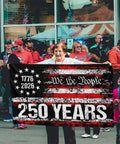 3 Ply 250 Year American Anniversary Flag being held by a person, 3x5 ft double-sided patriotic banner with We the People design.
