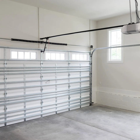 Interior of garage with white doors, overhead track system, highlighting garage door torsion spring mechanism.