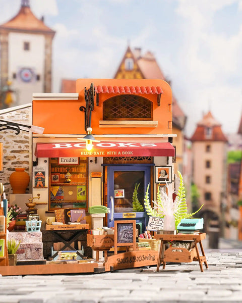 Front view of DIY Miniature Bookstore Kit 1 To 20 Scale With LED Lights Build Your Own Tiny House Craft Kit For Adults Totally Perfect Gift For Him Or Her Great Desk Display And Cozy Bedroom Decor, featuring colorful facade and small details.