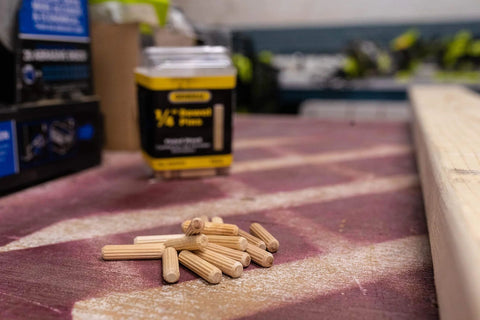1/4-Inch Fluted Wood Dowel Pins on workbench, 72 Count Pack, visible chamfered ends for easy insertion, FSC-certified hardwood.