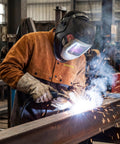 Rugged Full Grain Cowhide Welding Cape Sleeve With Kevlar Stitched Panels And Flame Resistant Barrier Against Flying Sparks And Hot Slag Shop Ready And Built To Go The Distance worn by welder creating sparks in workshop.