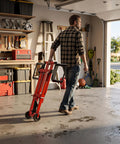 Man carrying Betisef 500 Lb Hydraulic Mower Lift Jack for Lawn Tractor in garage, designed for 40 to 47.6 inch axles.