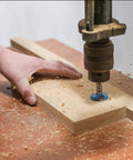 Side view of a Forstner drill bit, 45mm tungsten carbide, drilling a round hole in wood on a drill press.