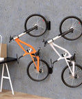 Rock Solid Swivel Bike Wall Mount Rack For Garage holding two bikes with rubber coated hooks on concrete wall, 2 pack.
