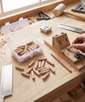 Clutch Pine Wood Pocket Hole Plugs And Slick Angled Fillers For Woodworking Repairs Crafted From Solid Timber With Smooth Surface For Garage Shop Projects Comes 50 Count In Sturdy Box laid out on a workshop table.
