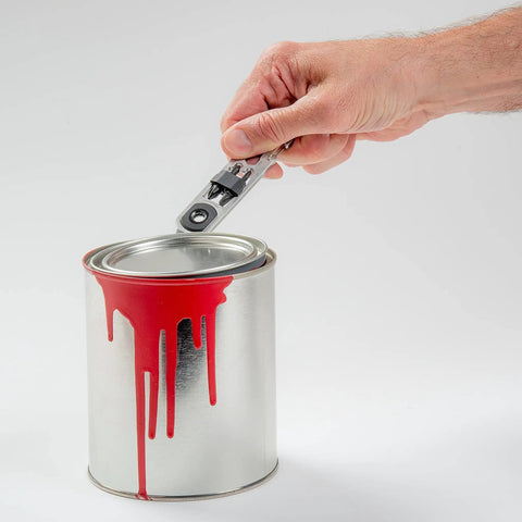 Hand using DoohicKey Ratchet Key Tool Keychain Friendly Pocket Multitool With Carabiner Clip to open paint can lid.