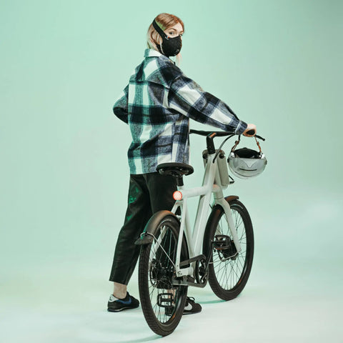 Person wearing Road Ready Nano Light Hexagon Motorcycle Half Face Mask With Anti Pollution Filter, standing beside a bicycle indoors.