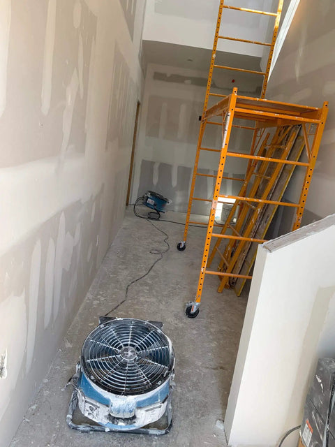 No Nonsense Heavy Duty Axial Air Mover Fan With Variable Speed Control And Three Hour Timer Pulling Maximum Cubic Feet Per Minute Through Wet Basement Spaces Blue positioned in unfinished hallway next to scaffolding.