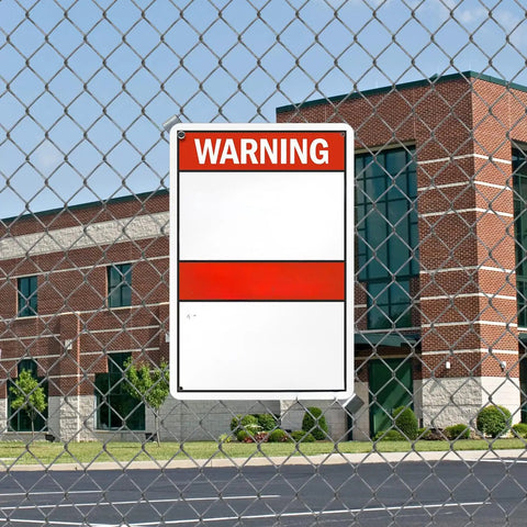 Warning sign on chain-link fence in front of a brick building