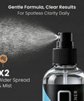 Front view of eyeglass cleaner spray bottle releasing mist; clear bottle, black label with blue accent