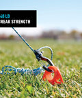 CamJam SlideLock Bungee Cord Tightener with pull to tighten lock and quick release lever securing cord in grass, 840 lb break strength.