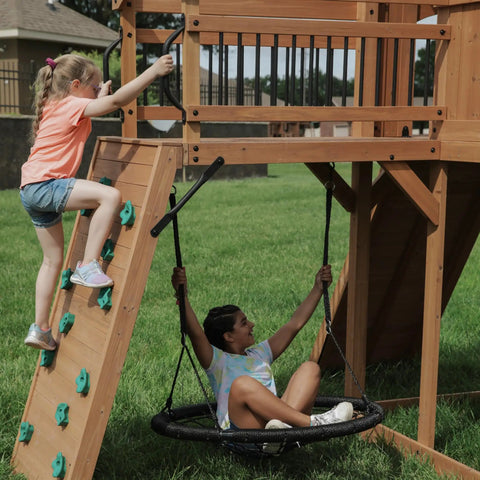 Children playing on Cedar Wood Swing Set With Wave Slide And Raised Clubhouse Plus Balcony, Wooden Bridge, Rock Wall, Belt Swings