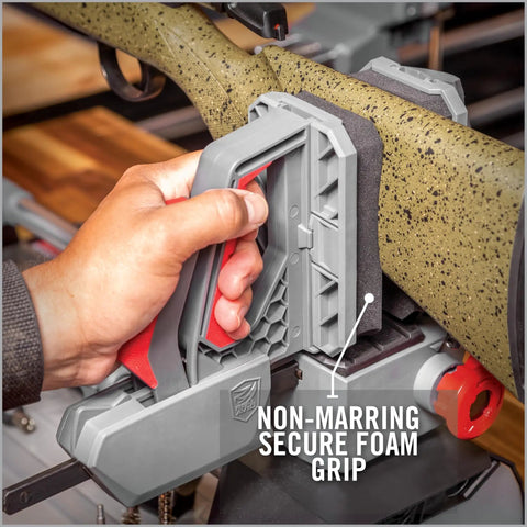 Hand holding One-Hand Clamp Gun Workstation with non-marring foam grip for secure firearm handling and maintenance.