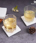 Solid White Square Marble Coasters Set Of Six, Polished Drink Pads for two glasses on a table with decorative items.