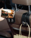 Sleek Double Purse Hook For Car, Universal Auto Seat Back Hanger, Premium Stitched Leather And Alloy Bag Organizer holding a phone and bag.