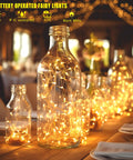 Six Pack Battery Operated Fairy Lights With Timer And Remote Six Point Five Foot Copper Wire 20LED Warm White Twinkle Lights inside glass bottles on table