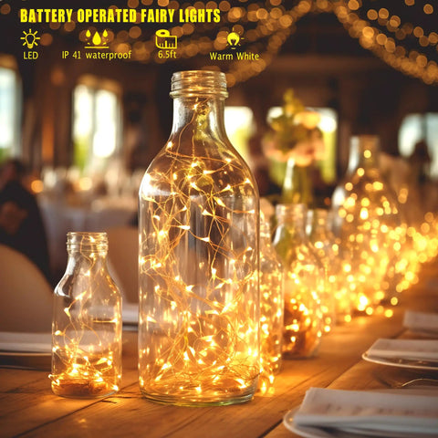 Six Pack Battery Operated Fairy Lights With Timer And Remote Six Point Five Foot Copper Wire 20LED Warm White Twinkle Lights inside glass bottles on table
