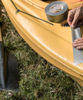 Person applying Duct Tape 1.88 Inch By 10 Yard Silver All Purpose Quick Fix Tape for Temporary Repairs on yellow kayak.