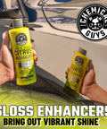 Person holding Citrus Wash & Gloss soap in front of car, part of Ultimate Car Wash Bucket Kit With Dirt Trap Insert, Microfiber Mitt, Soap, And Lid For Scratch Free, Swirl Free Washing, Heavy Duty Detailing Bucket System To Keep Your Car Looking Fresh.