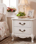 White nightstand with antique brass cabinet pulls, floral decor, and vintage photo frame