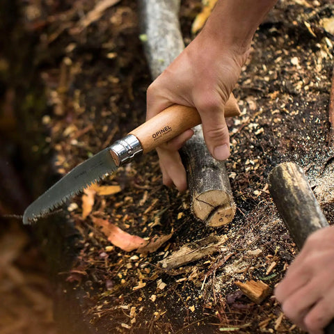 Badass Lightweight Folding Saw For Weekend Campouts And Garden Grind Cuts Branches Fast With Razor Sharp Carbon Steel Blade Secure Virobloc Lock And Natural Beechwood Handle in hand cutting a branch.