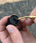 Close-up of Brass Inline Universal Nipple Pick For Muzzleloading Breech Cleaning in use on a black powder firearm part.