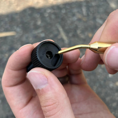 Close-up of Brass Inline Universal Nipple Pick For Muzzleloading Breech Cleaning in use on a black powder firearm part.