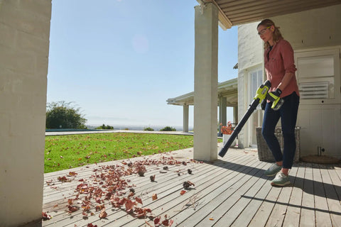 Person using the 18V One Plus Brushless Compact Blower Bare Tool With Variable Speed Trigger And Lock On for yard cleanup on a deck