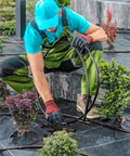 Man installing 394 Ft Drip Irrigation Kit For Garden And Lawn With 1/2 Inch Hose And 1/4 Inch Distribution Tubing in a garden