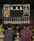 Industrial Iron And Raw Wood Wall Mounted Wine Rack featured above bar with wine bottles, glasses, and mugs hanging.