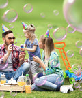 Family with Bubble Lawn Mower Toy With Realistic Sounds and bubbles in garden, toddler and parents in party hats on grass