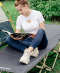 Heavy Duty Camping Cot For Adults No Fuss Setup Portable Folding Bed with person reading outdoors, near tent.