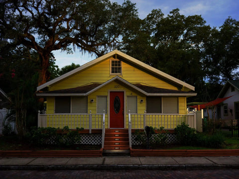 Charming yellow house with a porch and steps surrounded by trees