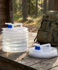 Two sizes of collapsible water container with spigot on wooden table, next to backpack. Collapsible Water Container With Spigot BPA Free Foldable Water Storage Jug With Handle Portable Water Carrier For RV Car Camping On The Go Hiking Picnic Emergency Use 0.8, 1.3, 2.6, 4 Gal.