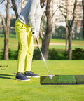 Person practicing golf on Tri Turf Golf Hitting Mat 24 By 24 Inch Portable Practice Mat for indoor and outdoor use with realistic 3 turf surfaces.