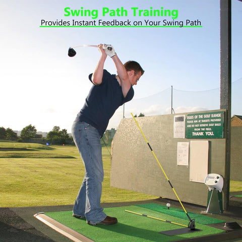 Man practicing golf swing with alignment sticks on driving range mat