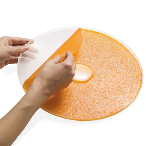 Smooth Operator Digital Electric Food Dehydrator With Stackable Trays showing a hand peeling orange fruit leather off a tray.