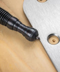 Close-up of Heavy Duty No Sweat Self Centering Screw Hole Punch With Hammerless Spring Action against metal and wood.