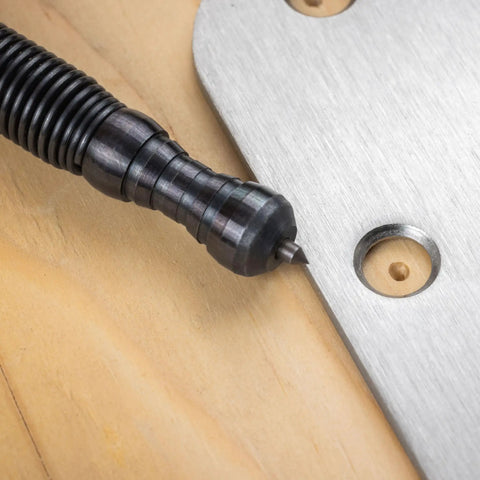 Close-up of Heavy Duty No Sweat Self Centering Screw Hole Punch With Hammerless Spring Action against metal and wood.