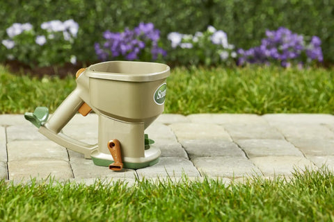 Hand Powered Lawn Spreader For Grass Seed Fertilizer Salt Ice Melt With Adjustable Arm Support on stone path