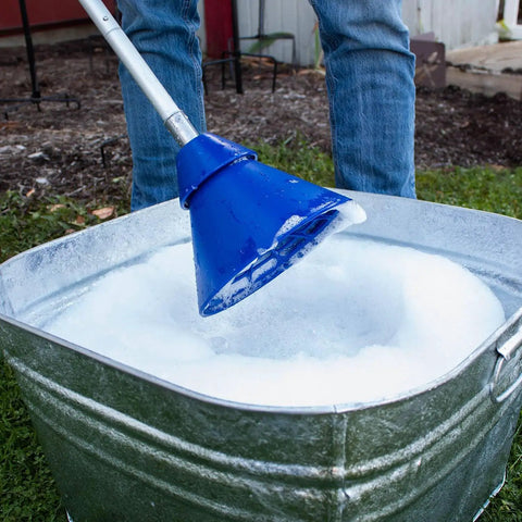 Portable Manual Clothes Washer Plunger Working As A Smooth Washing Agitator for bucket with soapy water in galvanized tub.