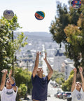 People shooting the Official DRV Series Basketball 27.5 Inch Size 5 in brown with rugged outdoor cover on a street.