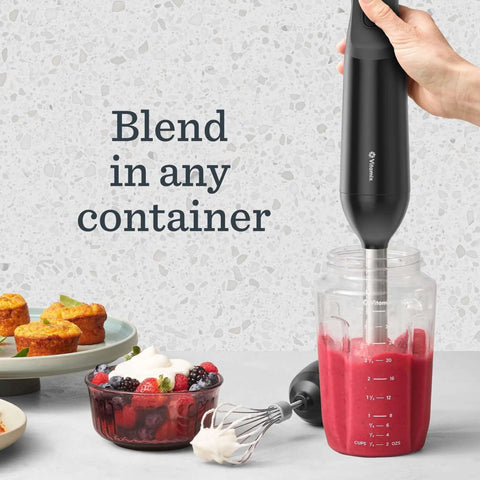 Slick Two Speed Immersion Blender With Whisk Attachment And Knockout 350 Watt Motor For Effortless Soup Blending Sauce Crafting And No Fuss Smoothie Mixing In Modern Black blending in a jar with fruits and desserts nearby.